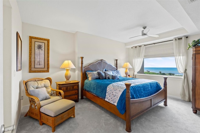 bedroom with ceiling fan, light carpet, and a water view