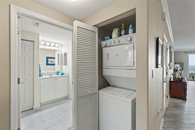 clothes washing area with visible vents, ornamental molding, laundry area, marble finish floor, and stacked washer / drying machine