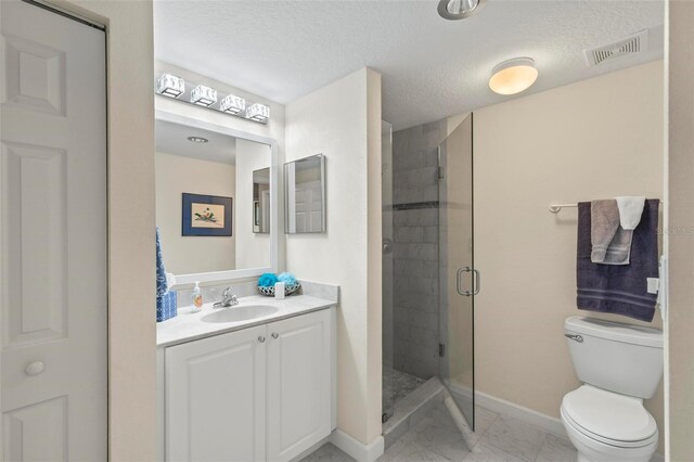 bathroom with vanity, tile patterned flooring, a textured ceiling, a shower with shower door, and toilet