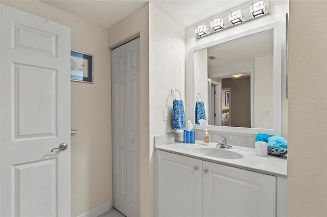 bathroom featuring a closet, baseboards, and vanity