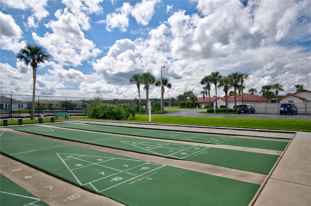 view of home's community with shuffleboard, a lawn, and fence