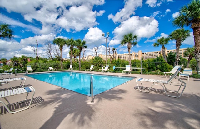 pool with a patio area and fence