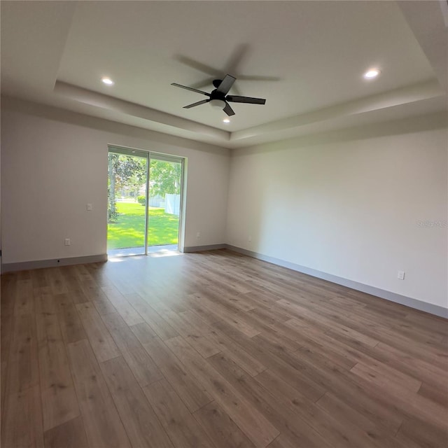 unfurnished room with a tray ceiling, ceiling fan, and hardwood / wood-style flooring