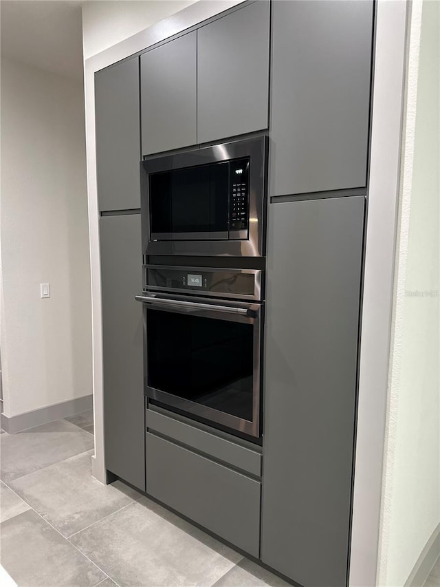 kitchen with gray cabinetry, light tile patterned floors, and stainless steel appliances