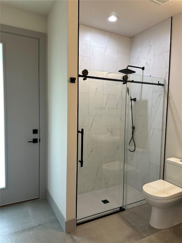 bathroom featuring tile patterned flooring, walk in shower, and toilet