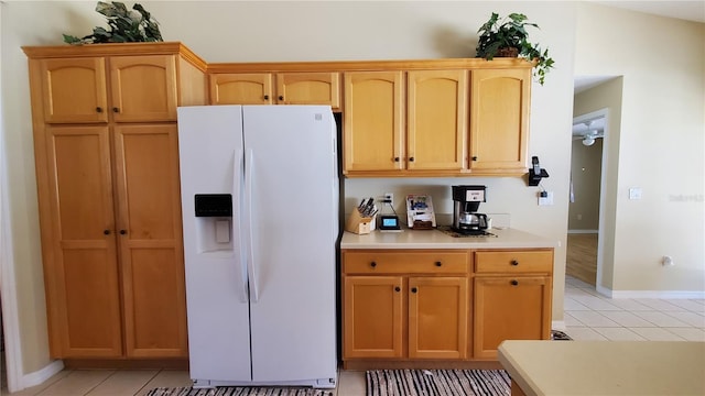 kitchen with white fridge with ice dispenser, vaulted ceiling, and light tile patterned flooring