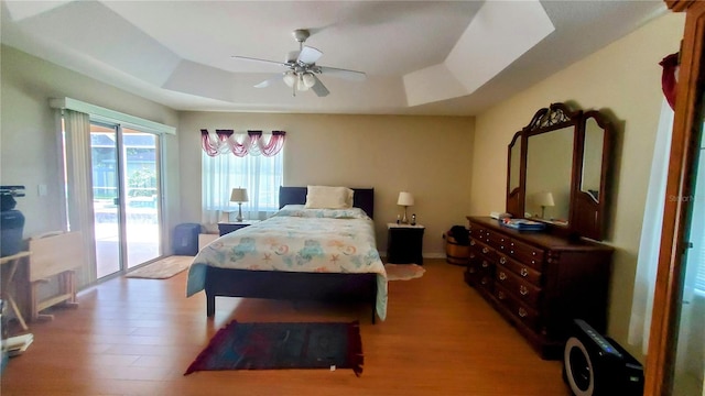 bedroom featuring hardwood / wood-style flooring, a raised ceiling, and access to outside