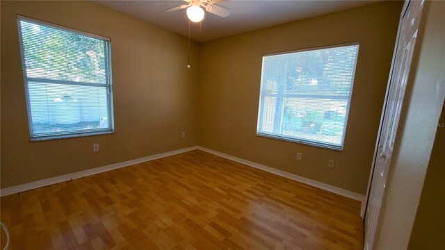 spare room featuring a wealth of natural light, hardwood / wood-style floors, and ceiling fan