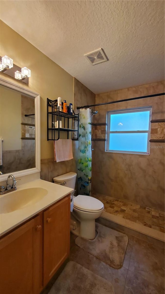 bathroom with toilet, tile patterned flooring, vanity, curtained shower, and a textured ceiling