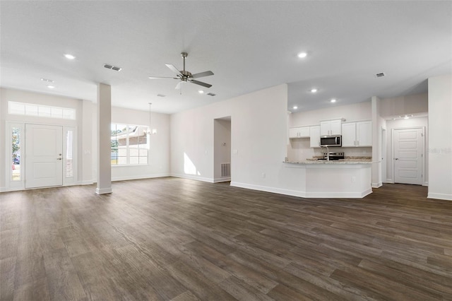 unfurnished living room featuring dark wood-type flooring and ceiling fan with notable chandelier