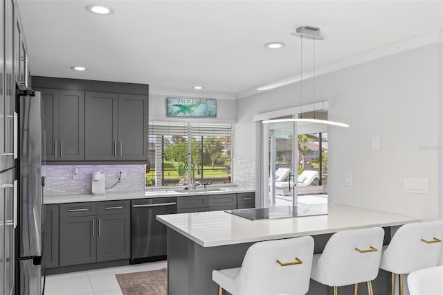 kitchen with a breakfast bar area, a peninsula, a sink, appliances with stainless steel finishes, and decorative backsplash