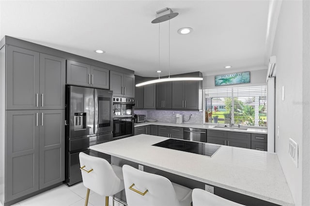 kitchen featuring hanging light fixtures, appliances with stainless steel finishes, backsplash, and a kitchen bar