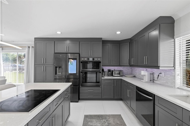 kitchen with light tile patterned floors, appliances with stainless steel finishes, tasteful backsplash, and gray cabinetry