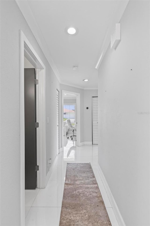 hall with ornamental molding, baseboards, and light tile patterned floors