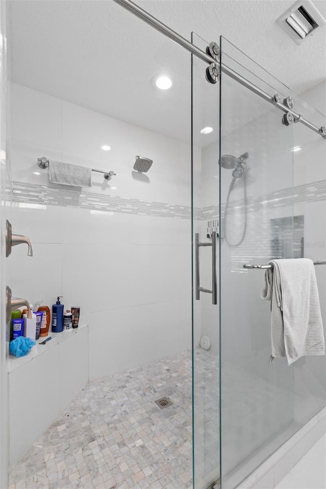 full bath with a textured ceiling, a shower stall, and visible vents
