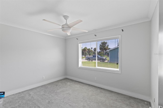 carpeted spare room featuring ceiling fan, crown molding, and baseboards