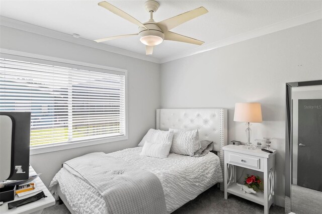 carpeted bedroom featuring ornamental molding and a ceiling fan