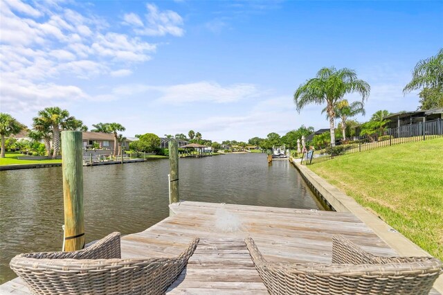 view of dock featuring a lawn and a water view