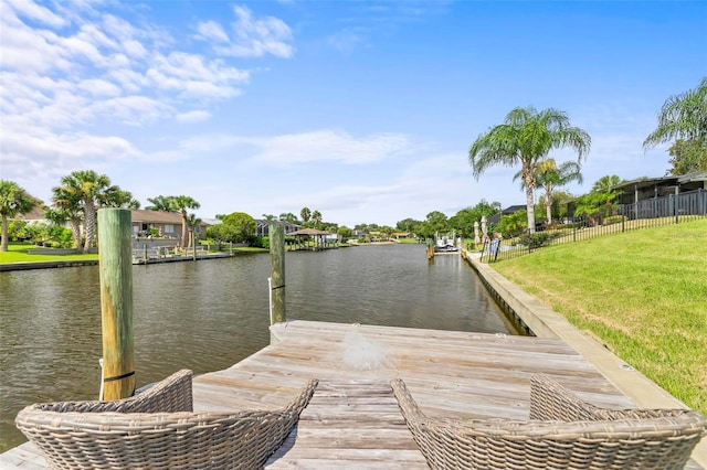dock area featuring a yard, a water view, and fence