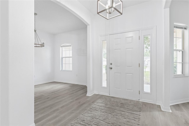 foyer with wood finished floors, plenty of natural light, and an inviting chandelier