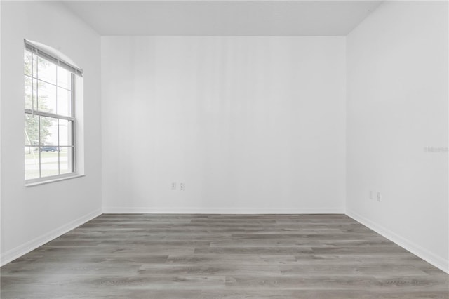 spare room featuring baseboards and wood finished floors