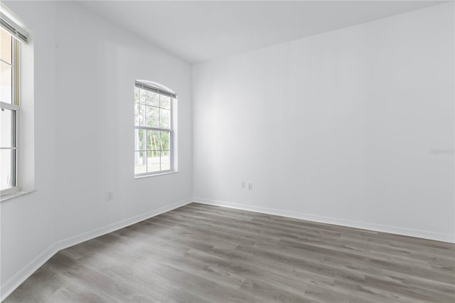 spare room featuring baseboards and wood finished floors