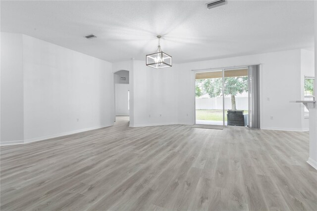 unfurnished living room featuring light hardwood / wood-style floors, a notable chandelier, and a healthy amount of sunlight