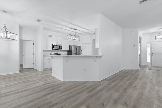 kitchen with arched walkways, stainless steel appliances, light wood-style flooring, white cabinets, and a chandelier