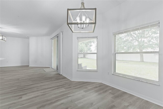 empty room with hardwood / wood-style floors and a chandelier