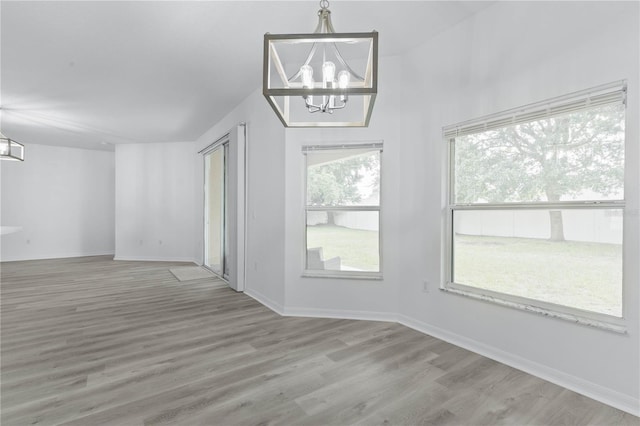 empty room featuring a chandelier, wood finished floors, and baseboards