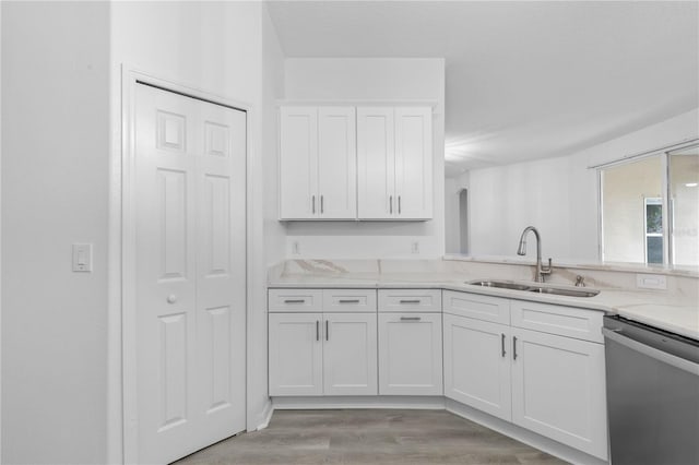 kitchen with sink, white cabinetry, stainless steel dishwasher, and light hardwood / wood-style floors