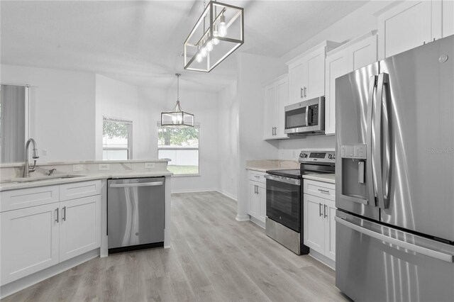 kitchen with stainless steel appliances, light hardwood / wood-style floors, sink, white cabinets, and hanging light fixtures