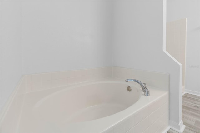 bathroom featuring hardwood / wood-style flooring and tiled tub