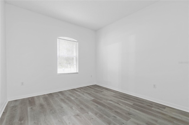 unfurnished room with baseboards and wood finished floors