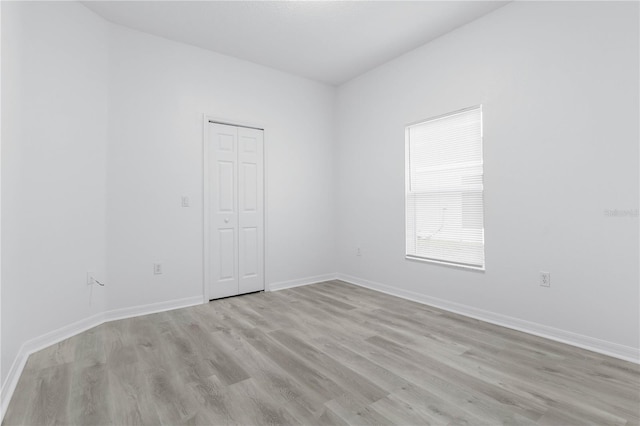 spare room featuring light wood-style floors and baseboards