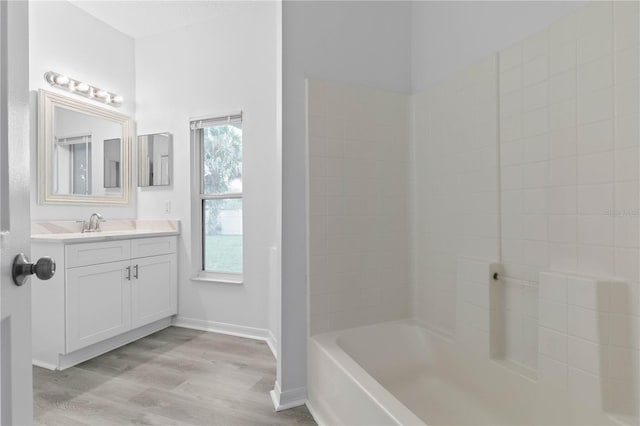 bathroom featuring bathing tub / shower combination, vanity, baseboards, and wood finished floors