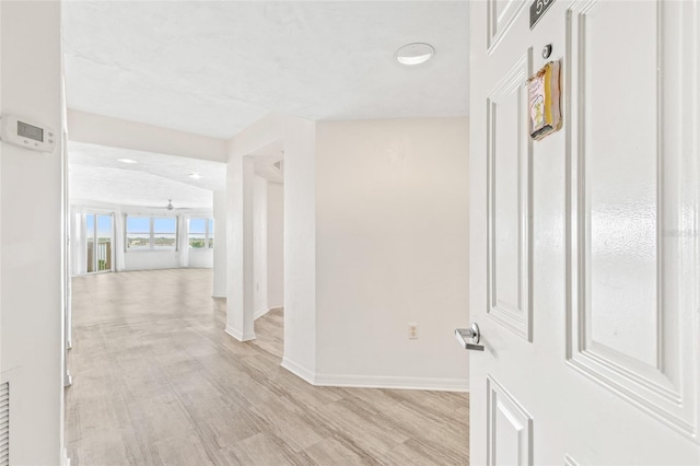 hallway with light wood-type flooring and baseboards