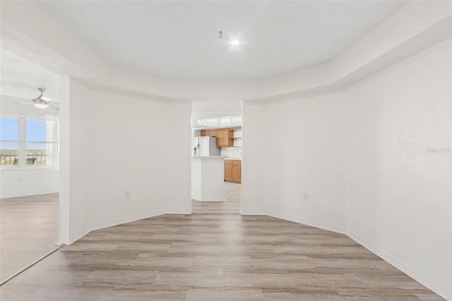 unfurnished room with ceiling fan, light wood-style flooring, and baseboards