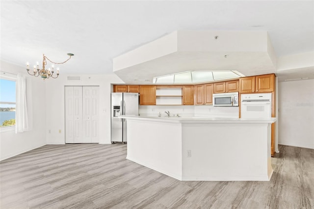 kitchen featuring light wood-style flooring, stainless steel appliances, light countertops, open shelves, and a sink