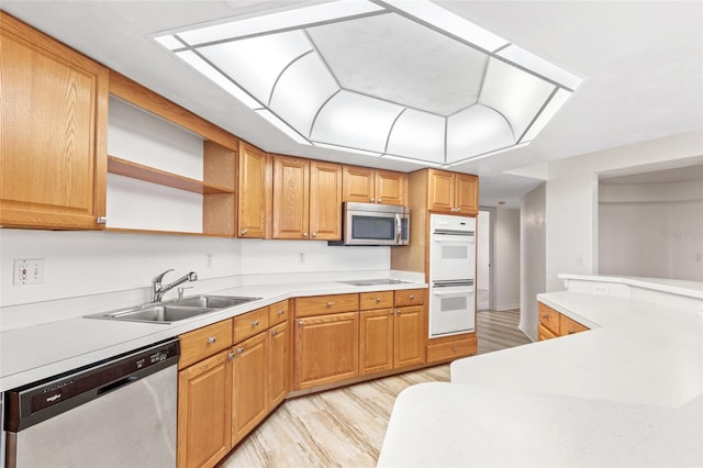 kitchen with open shelves, light countertops, appliances with stainless steel finishes, light wood-style floors, and a sink