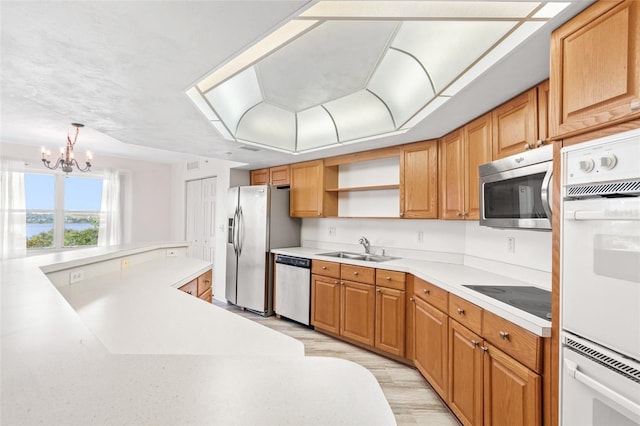 kitchen with a sink, light wood-style floors, light countertops, appliances with stainless steel finishes, and open shelves