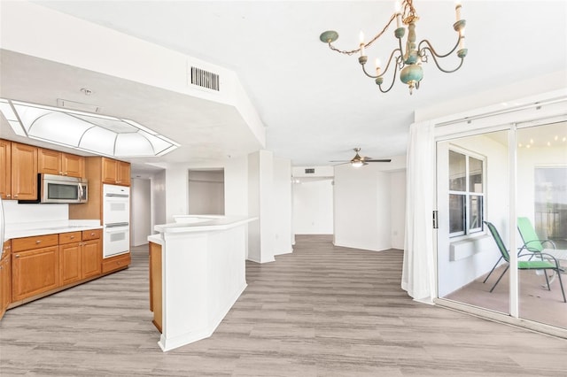 kitchen with white double oven, visible vents, light countertops, stainless steel microwave, and light wood-style floors