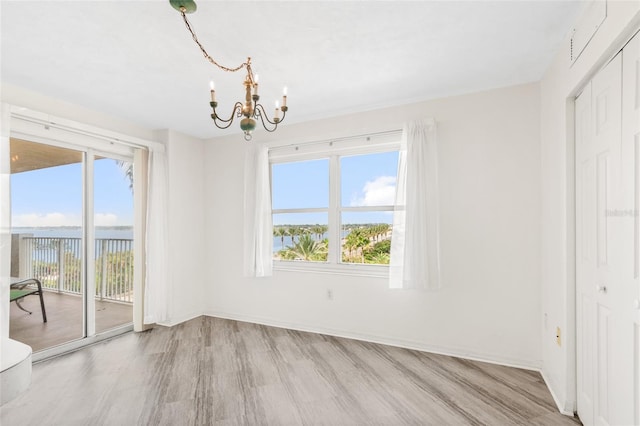 unfurnished dining area featuring baseboards, light wood finished floors, visible vents, and an inviting chandelier