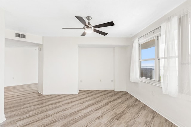 empty room featuring visible vents, ceiling fan, baseboards, and wood finished floors