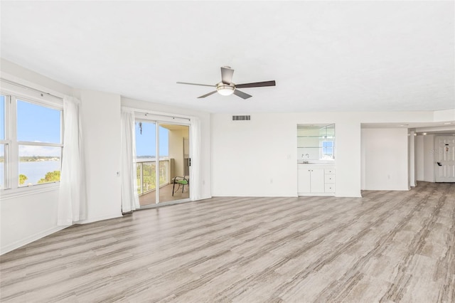 unfurnished living room featuring light wood-style flooring, a sink, visible vents, and a ceiling fan