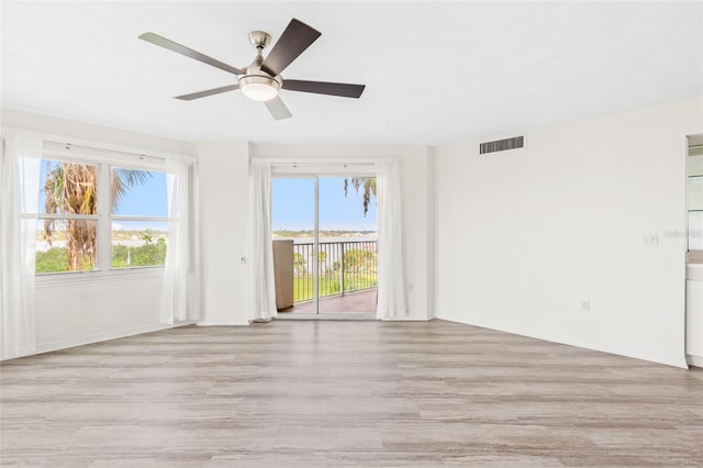 empty room with baseboards, light wood-type flooring, visible vents, and a ceiling fan