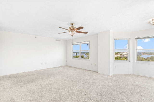 spare room featuring visible vents, plenty of natural light, a ceiling fan, and light colored carpet