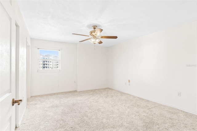 carpeted spare room featuring a ceiling fan