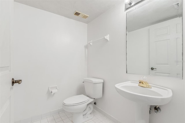 half bathroom with baseboards, visible vents, toilet, tile patterned floors, and a sink