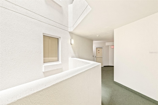 hall with dark carpet and baseboards